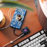 Shanling M0 Pura music player, with a phone on a keyboard