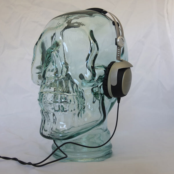 AMP3 glass skull headphone stand, clear, with headphones